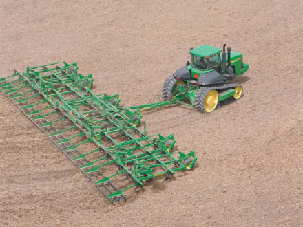 HD desktop wallpaper featuring a John Deere vehicle towing large green farming equipment across a plowed field.