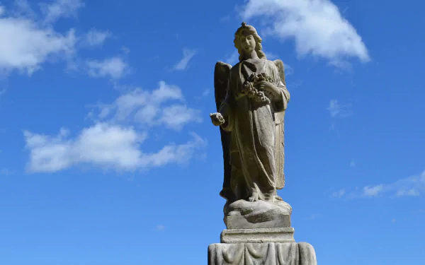 HD PC desktop wallpaper/background of a man-made religious angel statue on a pedestal against a bright blue sky with scattered clouds.