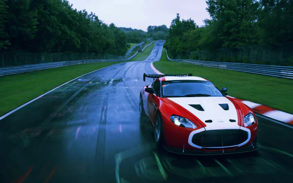 Red Aston Martin V12 Zagato vehicle racing on a wet track under an overcast sky — 2K Quad HD PC desktop wallpaper background.