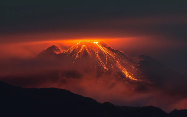HD PC desktop wallpaper showing a glowing volcano erupting at night, with lava flowing and surrounded by dark clouds and mist in a dramatic natural scene.