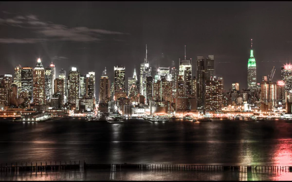 4K Ultra HD man-made skyline of New York City at night, featuring illuminated skyscrapers reflecting on the water.