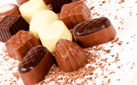 HD desktop wallpaper featuring an assortment of white, milk, and dark chocolates, garnished with chocolate shavings.