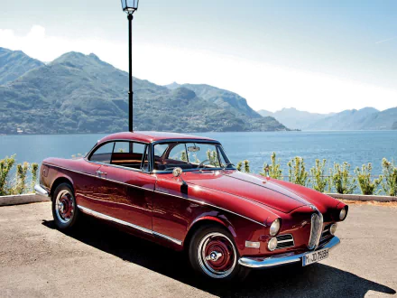 A classic red BMW 508 parked by a lakeside with mountains in the background, featured as a HD PC desktop wallpaper and background.