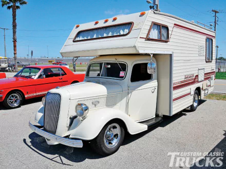 HD PC desktop wallpaper featuring a classic vintage motorhome parked outdoors alongside a red muscle car under a clear blue sky.
