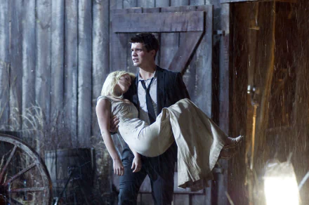 HD PC desktop wallpaper from the movie The Covenant (2006) featuring a man carrying a woman in front of a rustic wooden building at night.