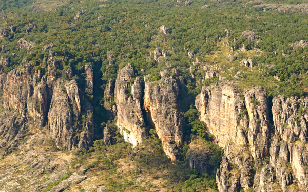 Aerial view of rocky cliffs and dense green vegetation in Kakadu National Park, showcasing the natural beauty of Kakadu in this HD desktop wallpaper.