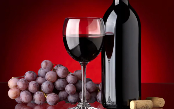A stunning HD wallpaper featuring a glass of red wine, a bottle, and a cluster of grapes against a rich red background, celebrating the theme of food and wine.