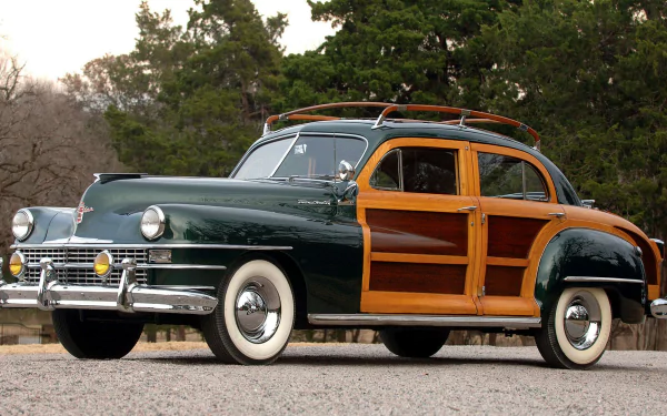 HD desktop wallpaper featuring a classic woody vehicle with wooden paneling parked outdoors against a backdrop of trees and greenery.