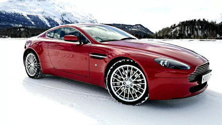 A red Aston Martin sports car parked on a snowy landscape with mountains in the background, showcased as a high-definition PC desktop wallpaper.