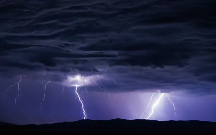 HD desktop wallpaper featuring dramatic lightning bolts streaking through dark storm clouds over a silhouetted landscape in a striking photography composition.