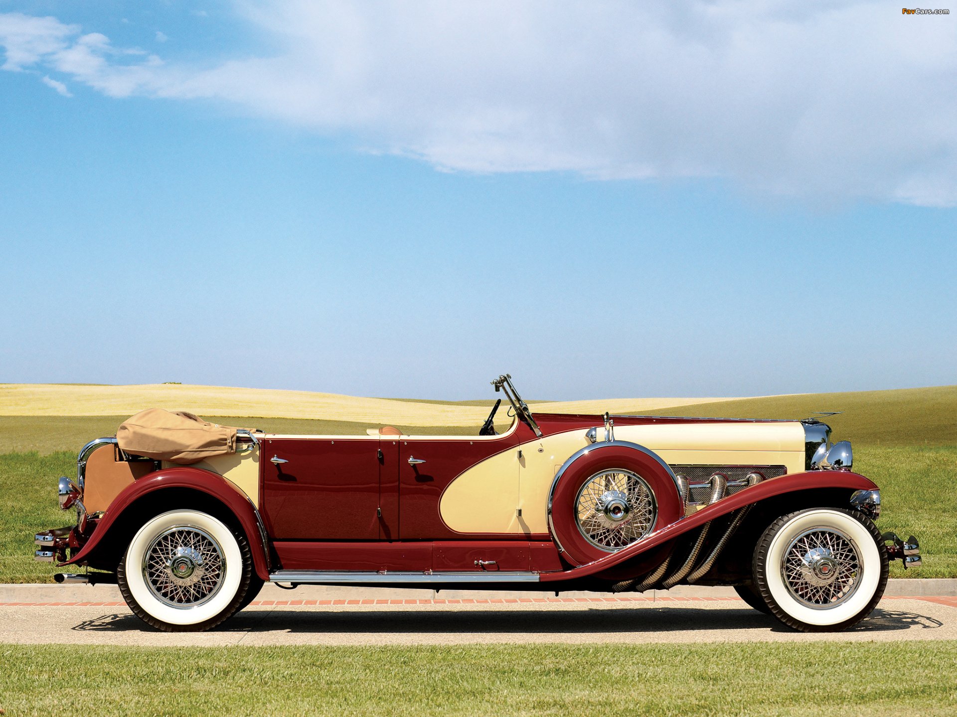 Red-and-cream Duesenberg convertible on a country road beneath a clear blue sky — HD PC desktop wallpaper/background.
