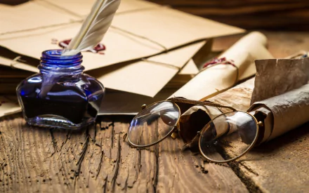 Vintage photography HD desktop wallpaper featuring a quill in ink, rolled parchment, and antique round glasses on a rustic wooden surface.