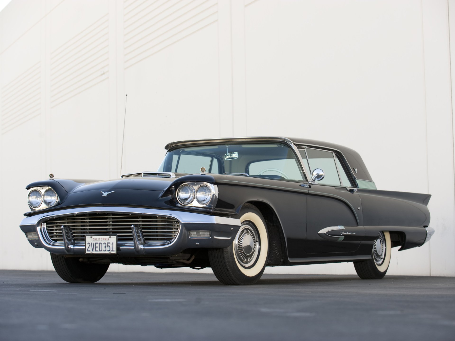 HD desktop wallpaper featuring a classic black Ford Thunderbird parked against a plain white wall, showcasing its vintage design and sleek lines.