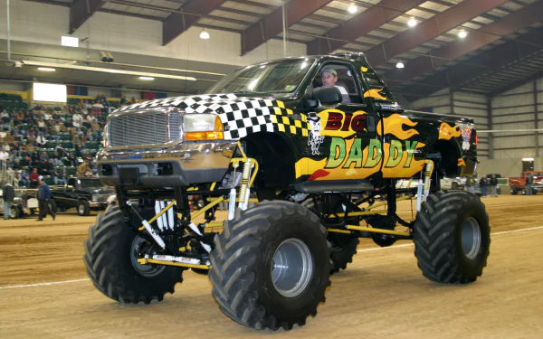 A vibrant monster truck, prominently featuring a checkered pattern and bold graphics, captured in action at an indoor arena, serves as an exciting HD desktop wallpaper and background.