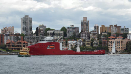 HD wallpaper showing the ABFC Ocean Shield, a Royal Australian Navy patrol vessel, sailing near Sydney with city buildings in the background.