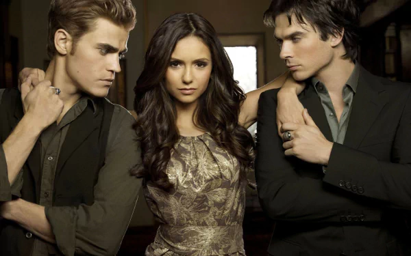 High-definition wallpaper featuring characters from The Vampire Diaries: a striking trio with a woman at the center, flanked by two men, set against a mysterious backdrop.