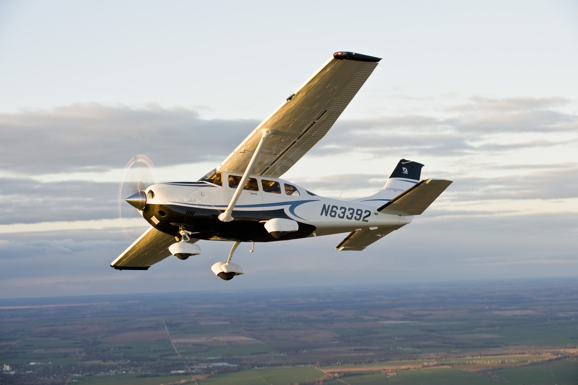 A Cessna aircraft flying over a landscape at sunset, captured in high definition for a PC desktop wallpaper background.