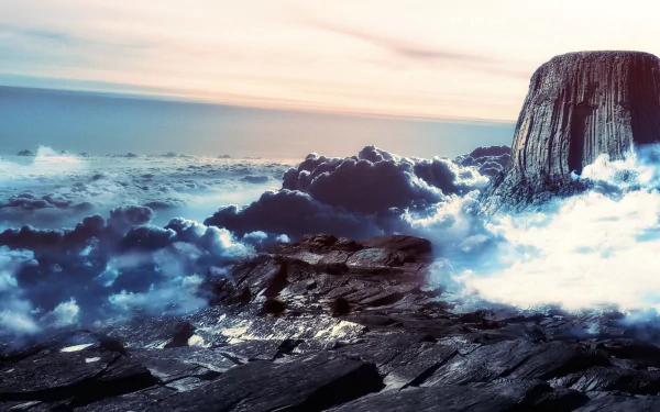 HD desktop wallpaper depicting Devils Tower amidst misty clouds, set against a dramatic sunset over rugged terrain.