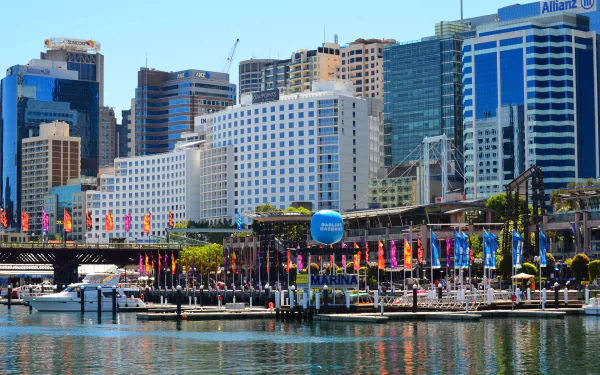 HD PC desktop wallpaper of Sydney's Darling Harbour: marina with boats, colorful flags and waterfront high-rise buildings reflecting on calm water.