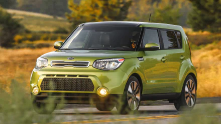 HD PC desktop wallpaper and background: green Kia Soul vehicle driving on a country road with blurred trees and golden fields under warm light.
