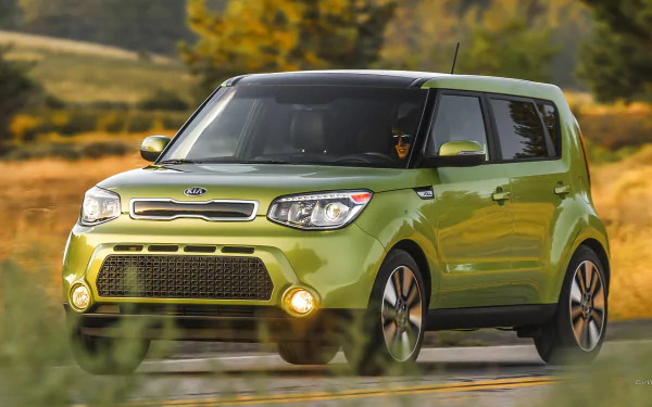 HD PC desktop wallpaper and background: green Kia Soul vehicle driving on a country road with blurred trees and golden fields under warm light.