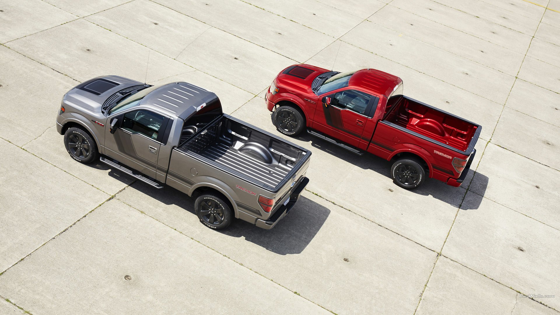 Two 2014 Ford F-150 Tremor trucks, one silver and one red, parked on a concrete surface, featured in a high-definition PC desktop wallpaper.