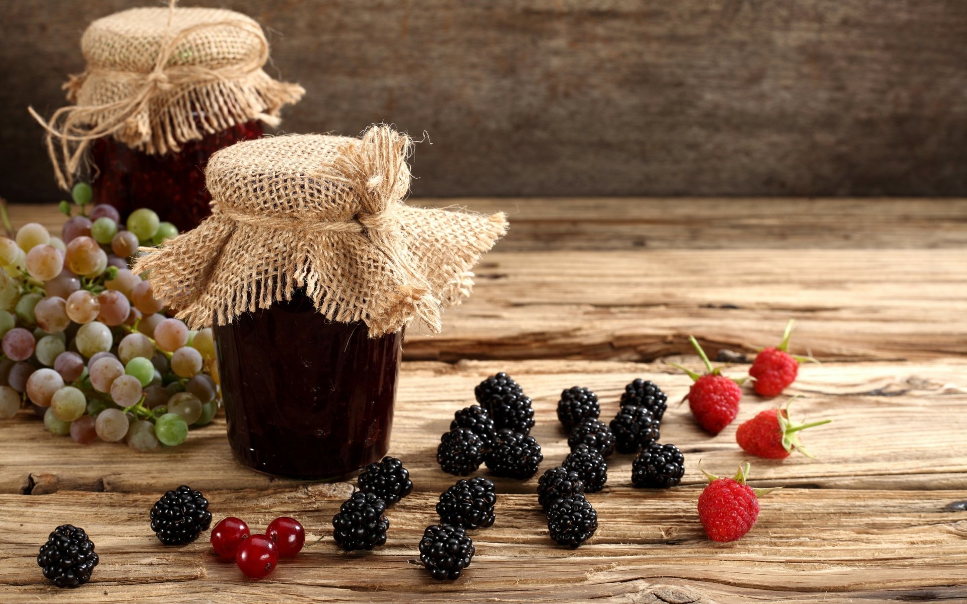 2K Quad HD PC desktop wallpaper: rustic jam jars and fresh blackberries, raspberries, red currants and grapes arranged on a weathered wooden table — food, jam.