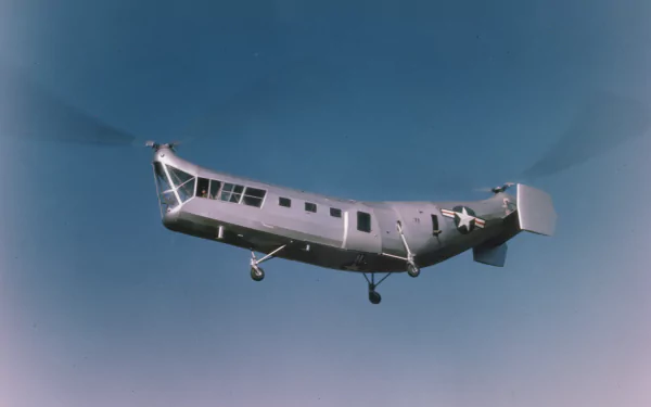 A military helicopter soars through a clear blue sky, captured in high definition, making an impactful desktop wallpaper or background.