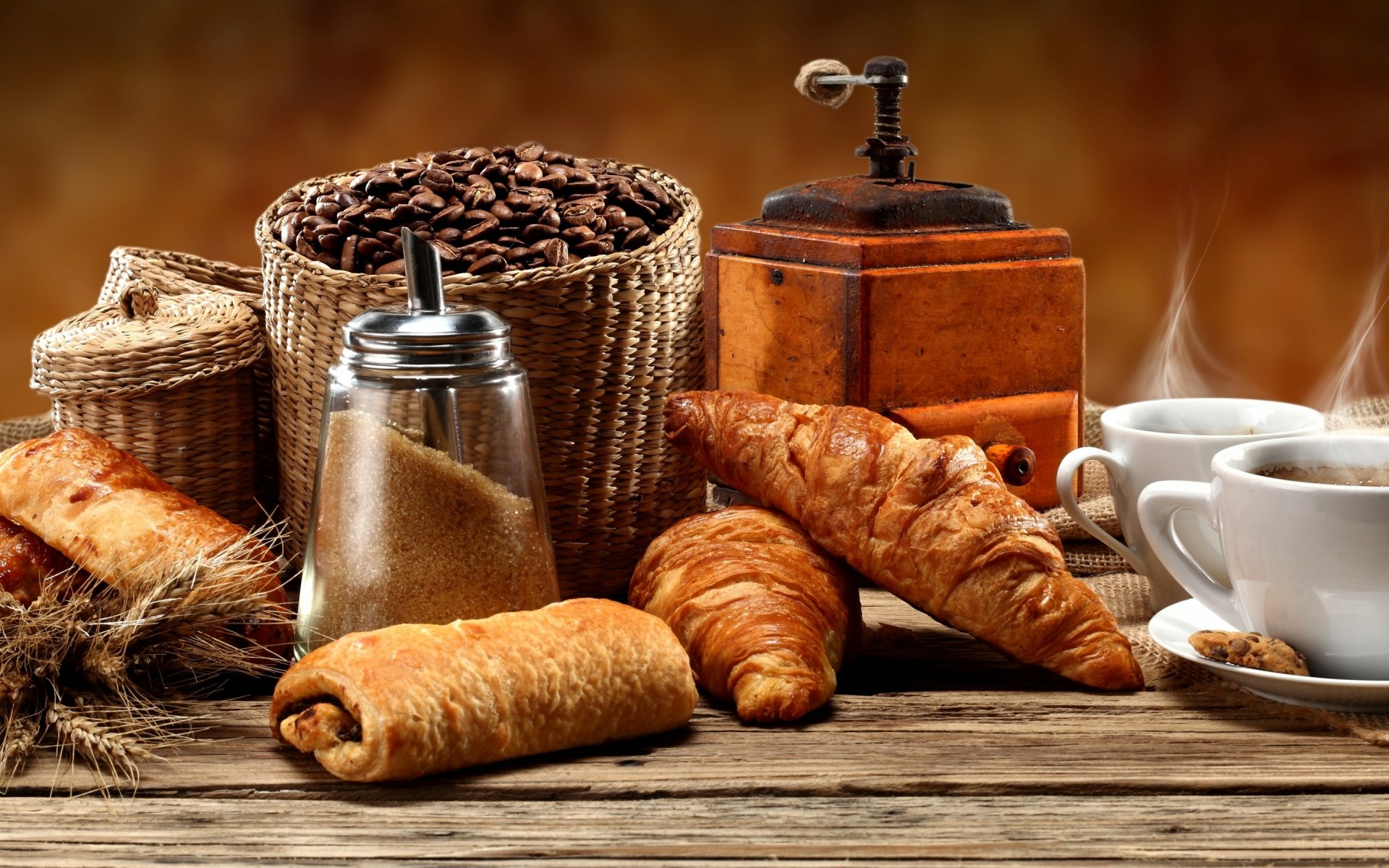 A cozy arrangement of coffee, pastries, and a vintage grinder, set against a warm background, creates an inviting food-themed desktop wallpaper.