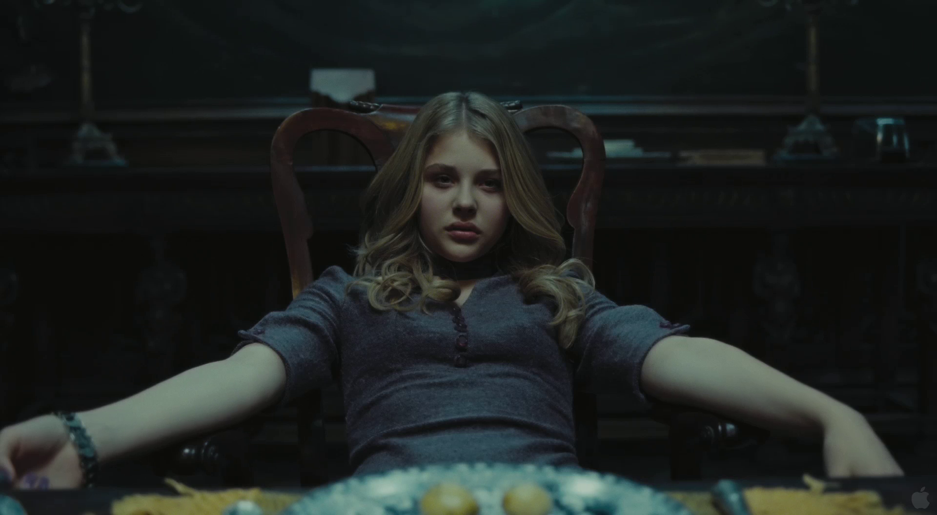 HD PC desktop wallpaper featuring a scene from the movie Dark Shadows with a young woman sitting in a dimly lit room, arms resting on chair sides.