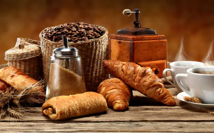 A cozy arrangement of coffee, pastries, and a vintage grinder, set against a warm background, creates an inviting food-themed desktop wallpaper.
