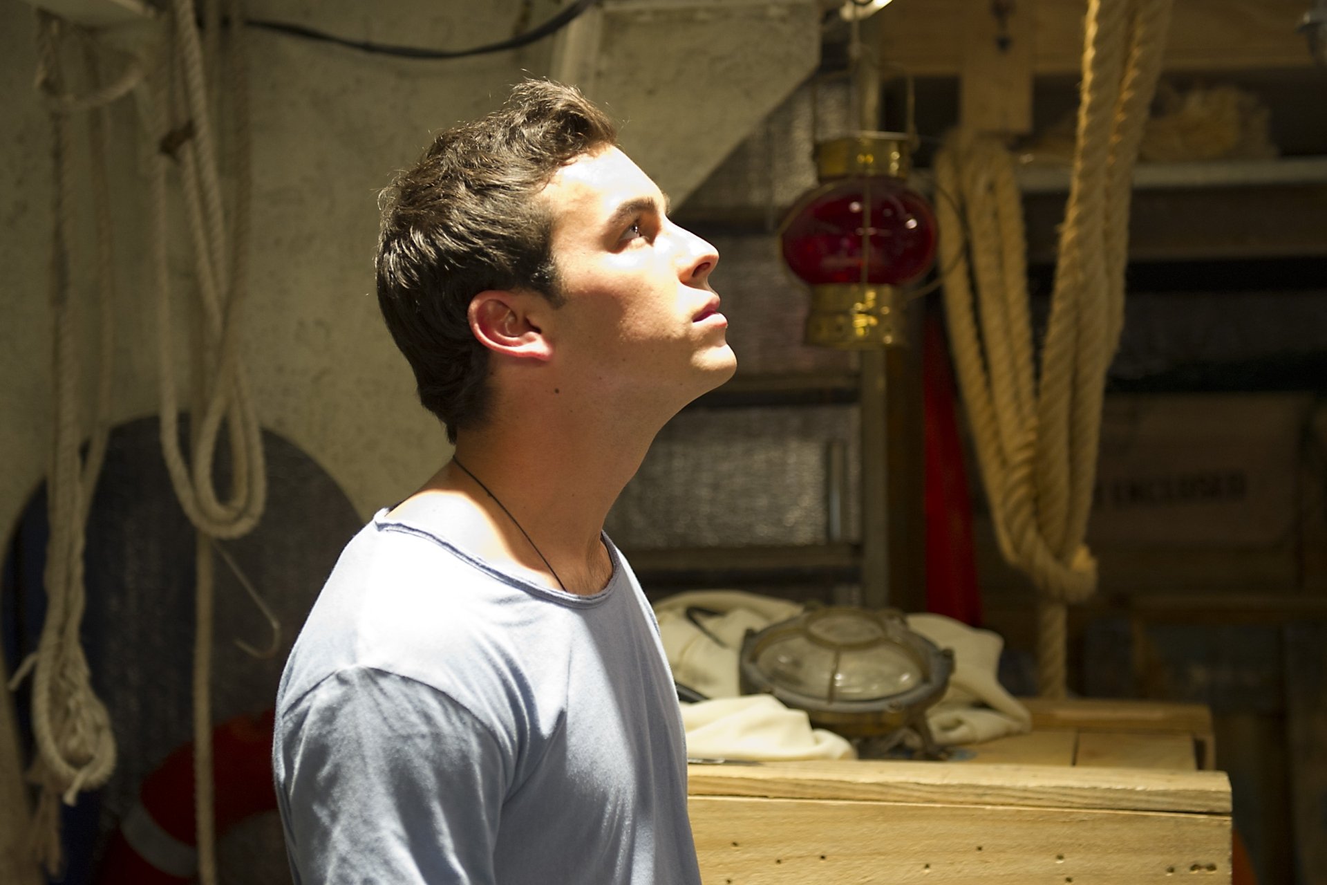 HD desktop wallpaper featuring celebrity Mario Casas in a softly lit room, looking upwards with a contemplative expression.