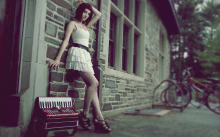 HD PC desktop wallpaper: woman in a white dress leaning against a brick building beside a vintage accordion and bicycles, moody green-toned outdoor scene.