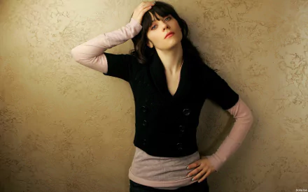 HD desktop wallpaper featuring celebrity Zooey Deschanel striking a casual pose against a textured beige background.