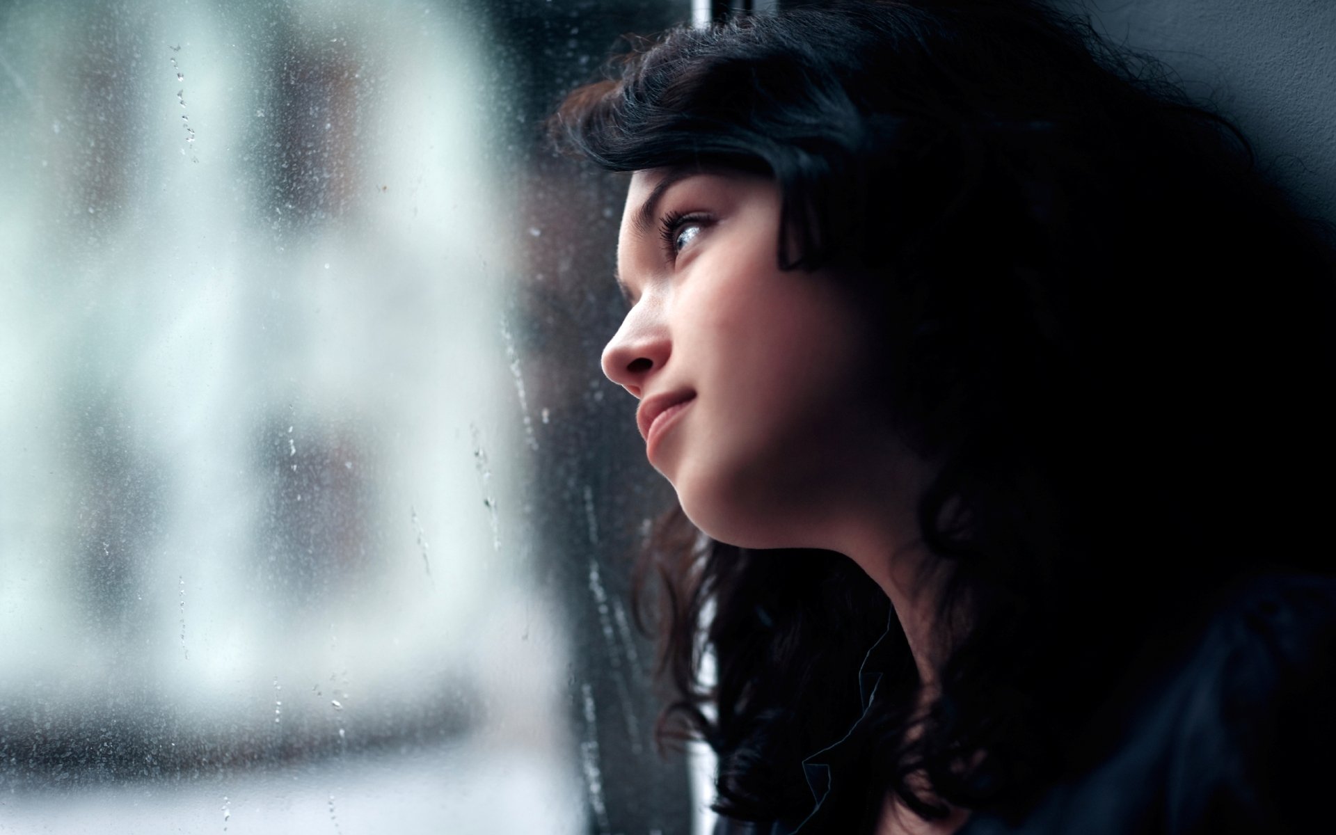 HD PC desktop wallpaper featuring a close-up of a woman’s face gazing thoughtfully out a window with a soft, blurred background.
