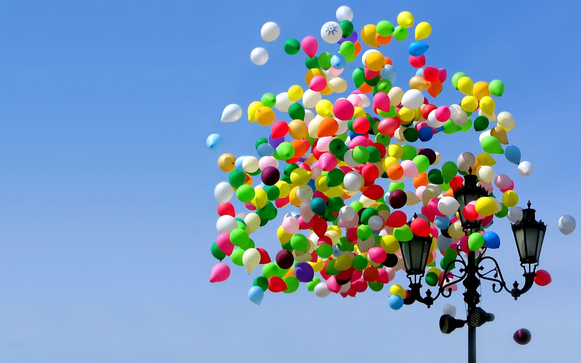 HD desktop wallpaper featuring a cluster of colorful balloons floating above a street lamp against a clear blue sky.