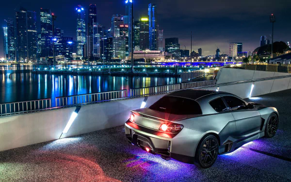 HD PC desktop wallpaper featuring a sleek Mazda RX-8 with glowing underlights, parked by a waterfront overlooking a vibrant city skyline at night.