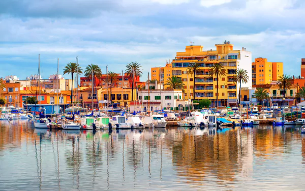 HD desktop wallpaper of a vibrant Palma de Mallorca harbor with boats docked and colorful man-made buildings reflecting on calm water.