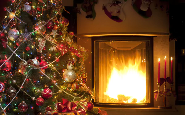 HD wallpaper featuring a decorated Christmas tree with lights and ornaments beside a glowing fireplace, creating a cozy holiday scene.
