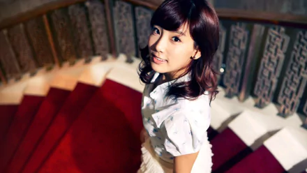 I don't know who this is. Alt: Smiling Korean woman on a red spiral staircase — HD desktop wallpaper evoking an actress, dancer, TV presenter and K-pop singer (Girls' Generation–inspired).