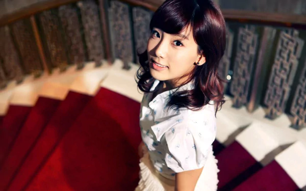 I don't know who this is. Alt: Smiling Korean woman on a red spiral staircase — HD desktop wallpaper evoking an actress, dancer, TV presenter and K-pop singer (Girls' Generation–inspired).