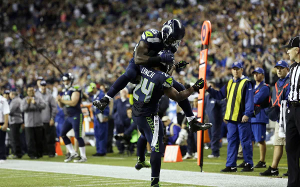 Seattle Seahawks players celebrate a touchdown during a game, showcased in a vibrant 4K Ultra HD PC desktop wallpaper and background.