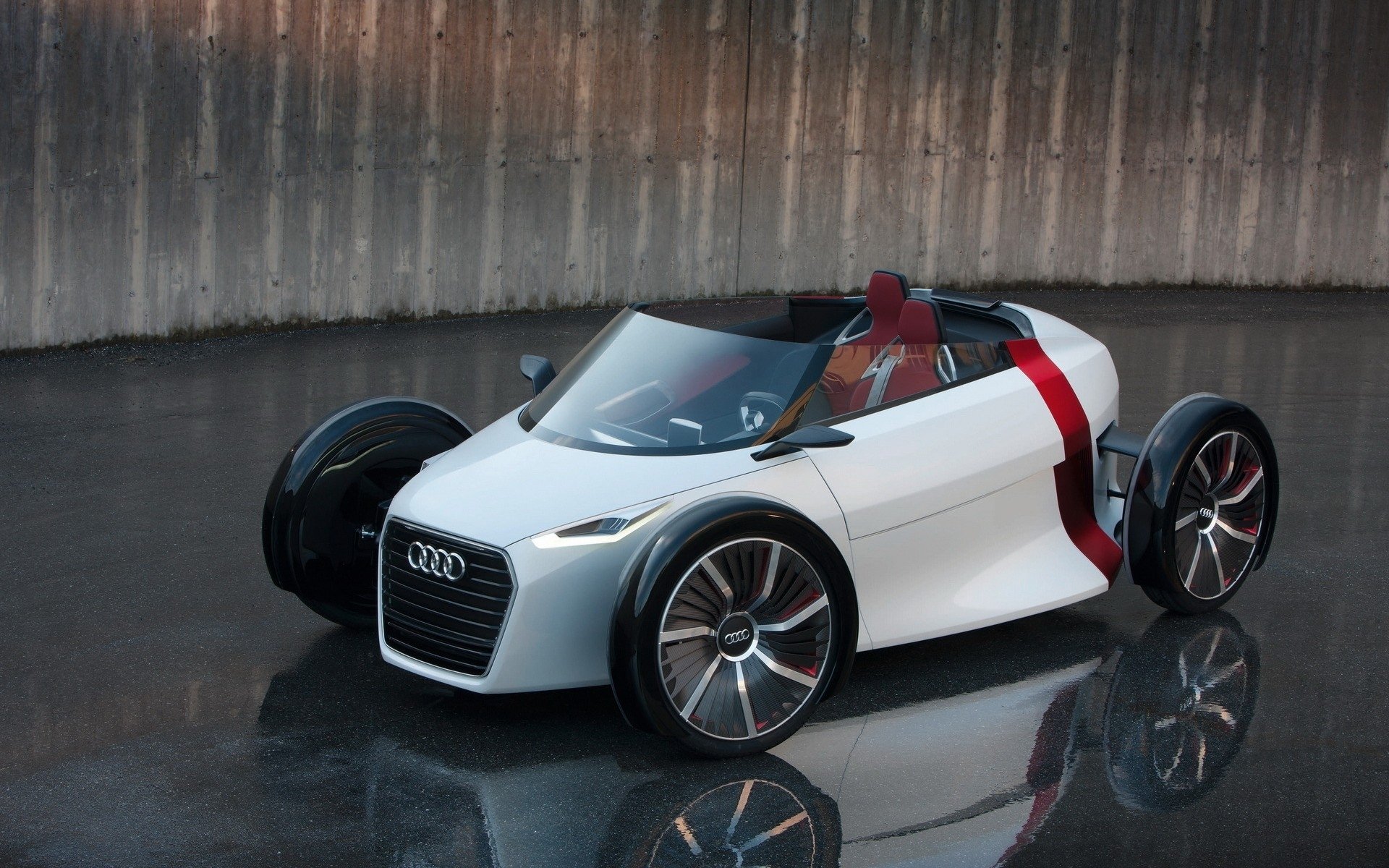HD PC desktop wallpaper featuring a sleek white Audi urban vehicle with futuristic design elements against a reflective dark surface and concrete backdrop.