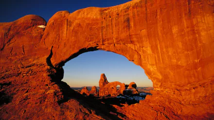 HD PC desktop wallpaper featuring a natural rock arch formation with a vibrant orange hue against a clear blue sky in a scenic nature setting.