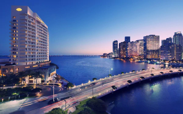 Night view of Miami’s man-made waterfront with illuminated buildings and a curving bridge, captured in HD for a desktop wallpaper background.