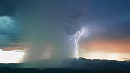 HD desktop wallpaper featuring a striking lightning bolt illuminating a stormy landscape at twilight.