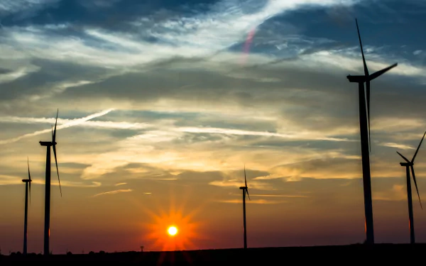 4K Ultra HD desktop wallpaper featuring man-made wind turbines silhouetted against a vibrant sunset sky with scattered clouds.