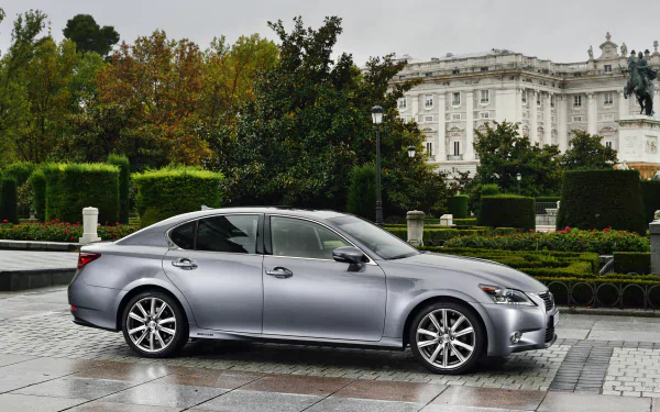 HD desktop wallpaper featuring a sleek silver Lexus GS 300h parked in front of a grand historic building with lush greenery in the background.