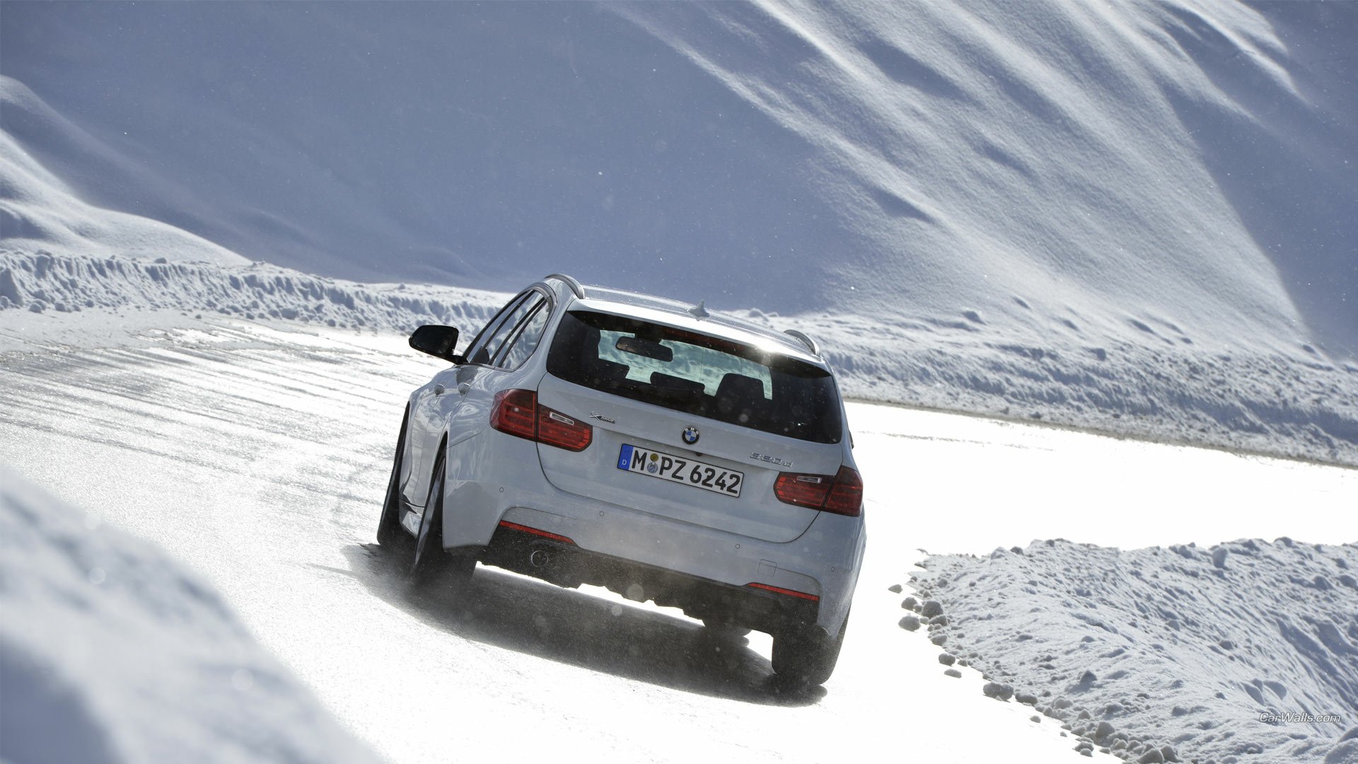 White 2013 BMW 320d driving on a snow-covered mountain road, rear view, high-definition PC desktop wallpaper/background.