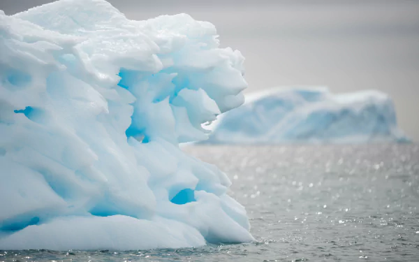 A serene view of an iceberg floating in calm waters, captured in stunning 4K Ultra HD, showcasing the beauty of nature's icy formations.